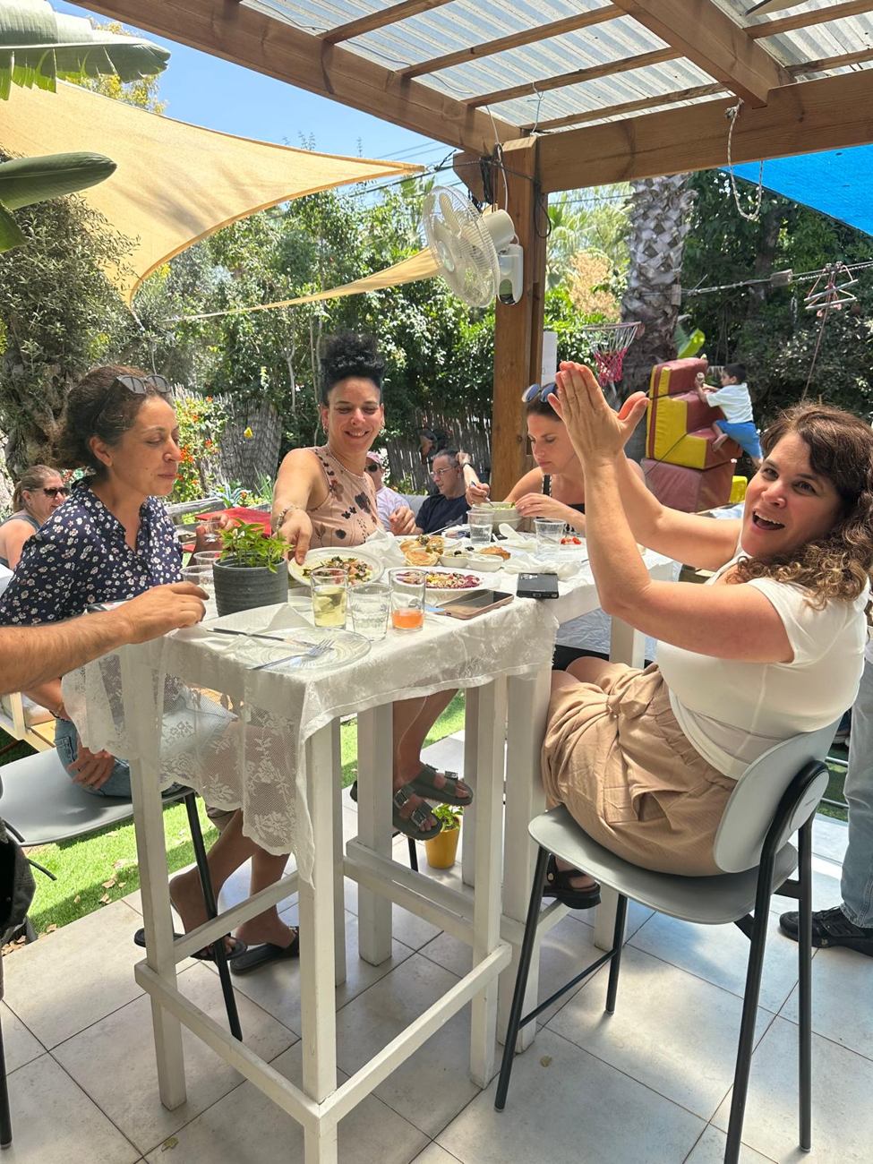 חברים סביב שולחן באור יום בחצר